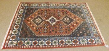 A Caucasian style Wool Carpet, central panel of lozenges, mainly iron red and blue/grey field, 5’