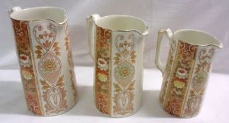 A graduated set of three Ford & Sons Jugs of spreading cylindrical form, each decorated in colours