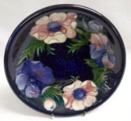 A Moorcroft Circular Plate, decorated with an “Anemone” design on a dark blue ground, impressed