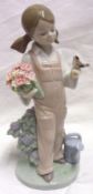A Lladro Model of a young girl wearing dungarees clutching flowers under one arm and with a bird