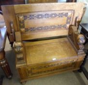 An unusual 20th Century Oak Monks Bench, the swivelling top raised on grotesque mask supports with a