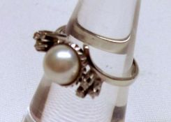A high grade precious metal Ring, set with a centre Pearl flanked to each side by a trefoil of three