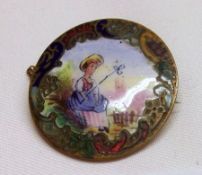 A gilt metal Circular Brooch, enamelled with a country girl within a scrolled surround (with