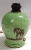 A small Torquay Ware Pottery Lamp, decorated in treacle with a landscape scene on a pale green