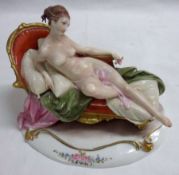 A Naples (Capodimonte) Model of a reclining nude on a chaise longue, painted throughout in