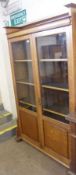 An Oak Bookcase, possibly for Liberty & Co, plain top over two ¾ glazed doors enclosing fitted