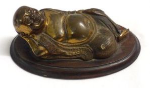 A Bronze Patinated Copper Model of a reclining Oriental Figure, on a treen base, 6 ½” long