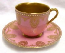 A Worcester Coffee Cup and Saucer gilded with swags and garlands on a puce ground, within cream