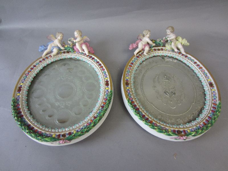 Near pair of late C19th Meissen mirrors, the identical frames surmounted by winged putti 32h x 24w