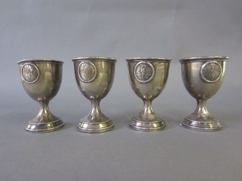 Set of four hallmarked silver egg cups with embossed golfing scenes