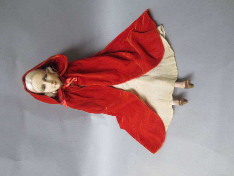 Late C20th ceramic & material doll with ivory coloured velvet dress & red riding cape 74H