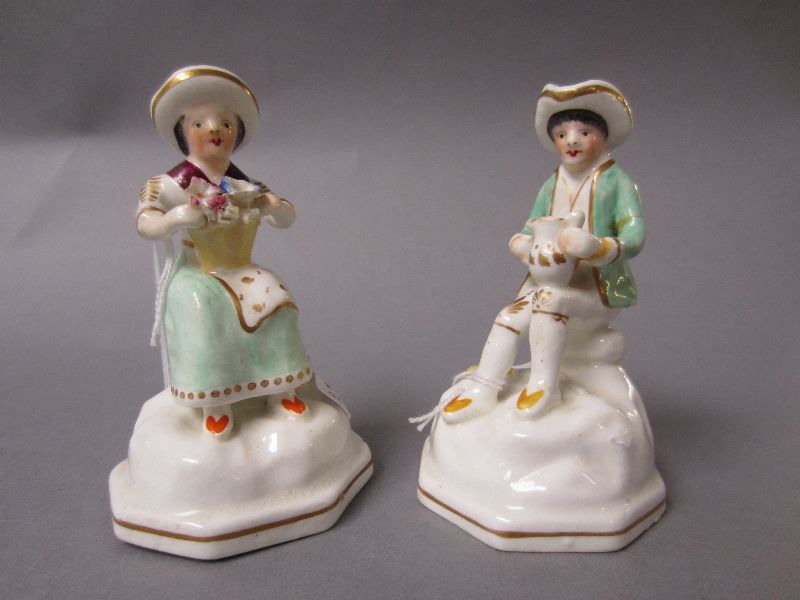 Pair of C19th Rockingham style figures on octagonal bases as a gilt with a basket of flowers & a boy