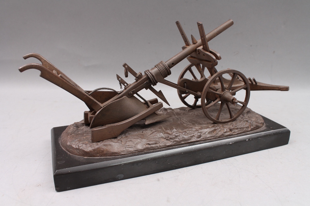 An iron scale model of a 19th century plough, on slate base, 27cm wide overall.