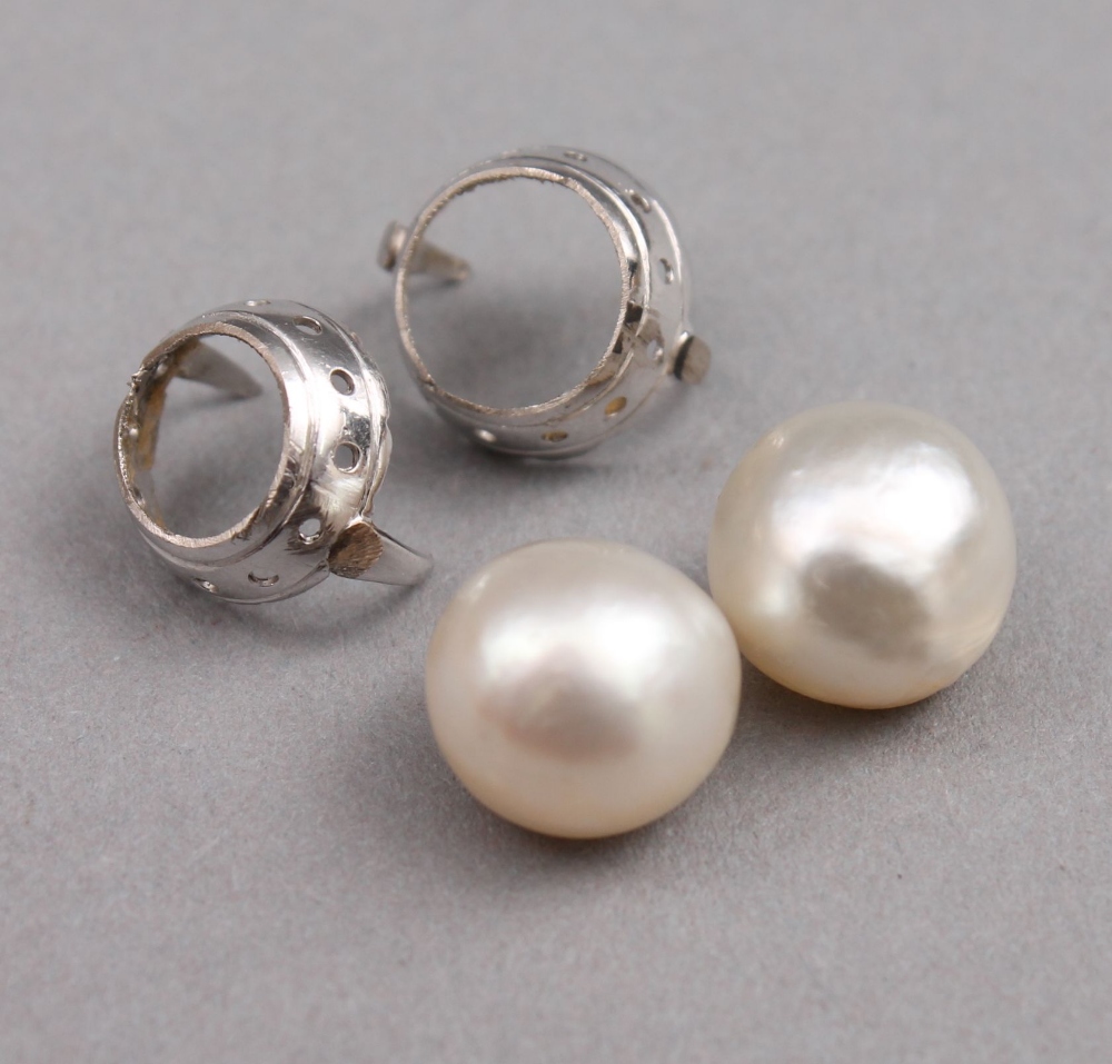 A pair of pearls with white metal coronet mounts the three quarter off round button shaped pearls