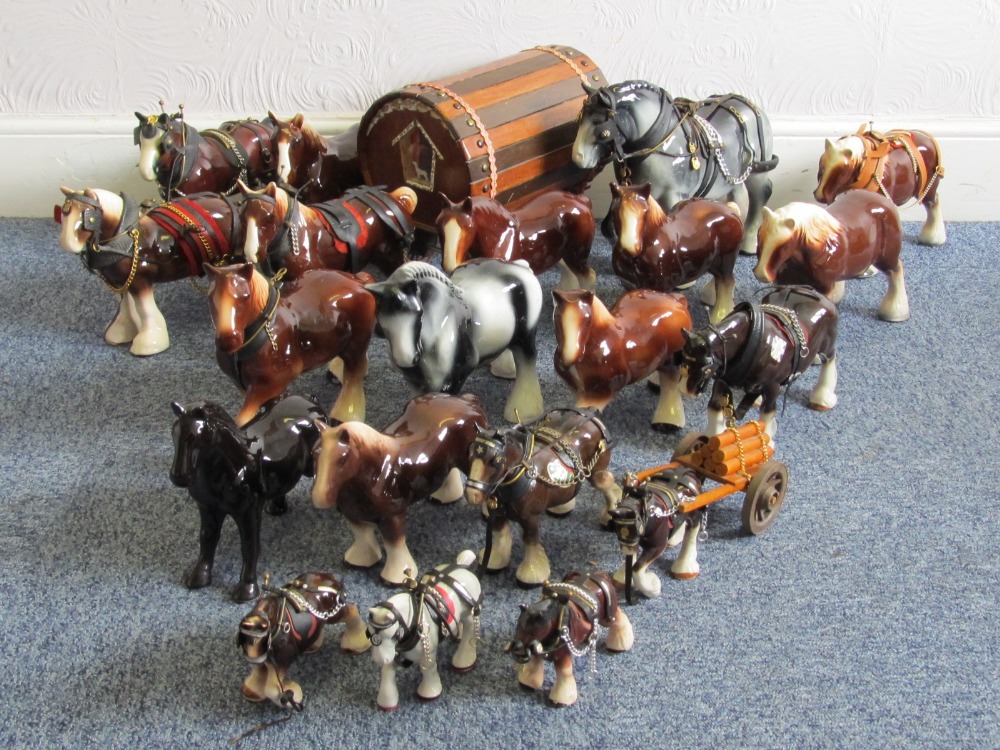 A collection of nineteen ceramic shire horses, varying sizes, and a caravan.