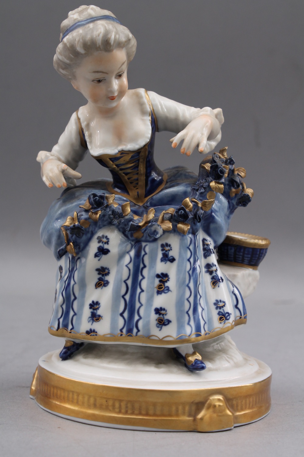 A Continental polychrome and gilt decorated porcelain figure of a girl, 15cm high, marked to base `