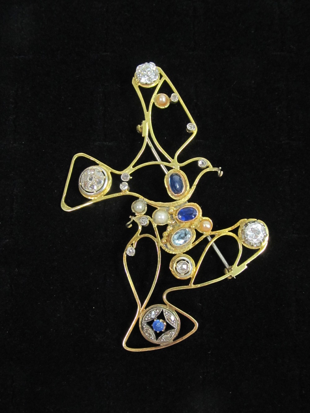 A diamond and coloured gemstone set brooch, the abstract open wire work design depicting stylised