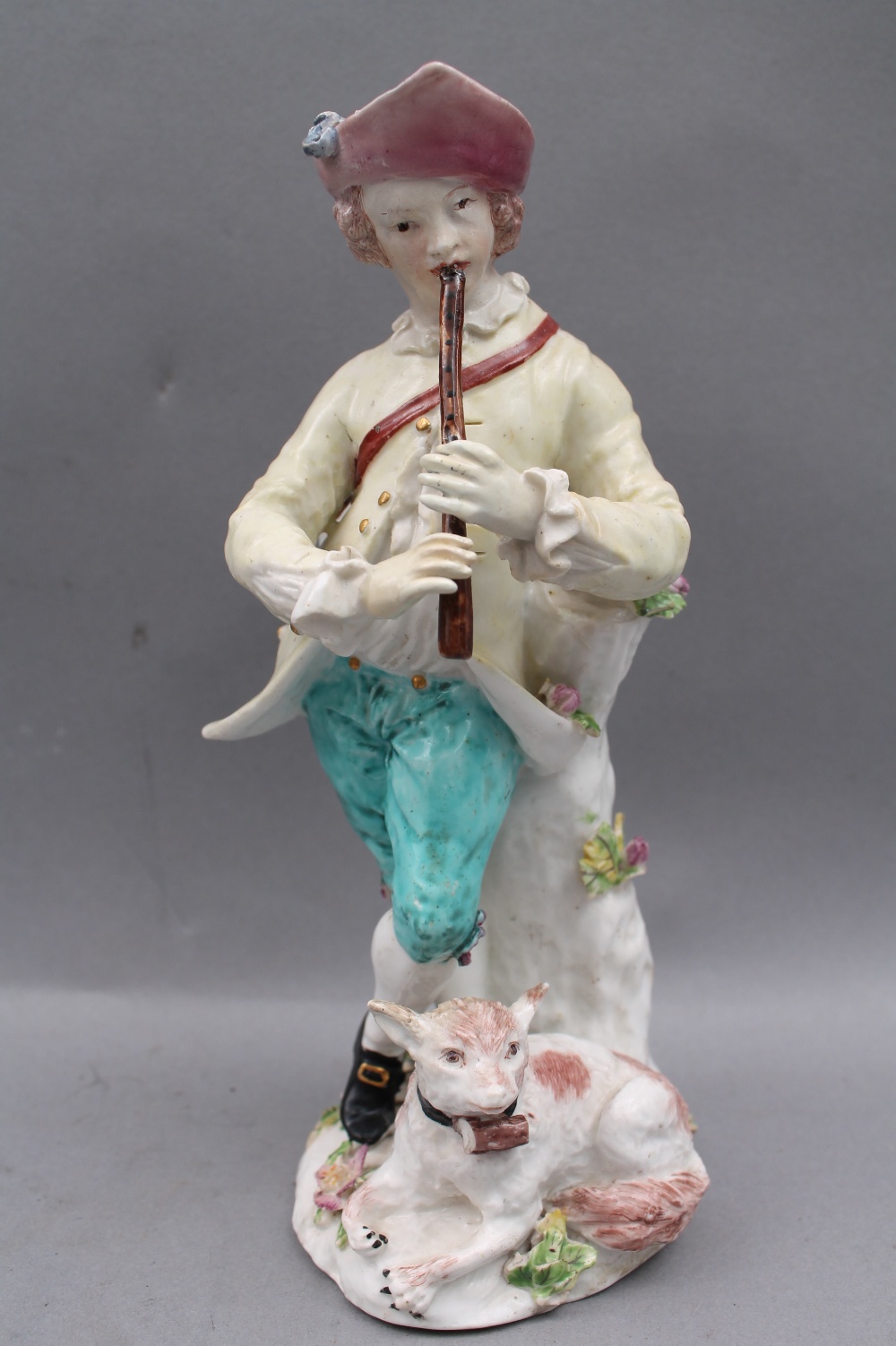 An 18th century porcelain figure of a musician, probably Bow, modelled with attendant dog (