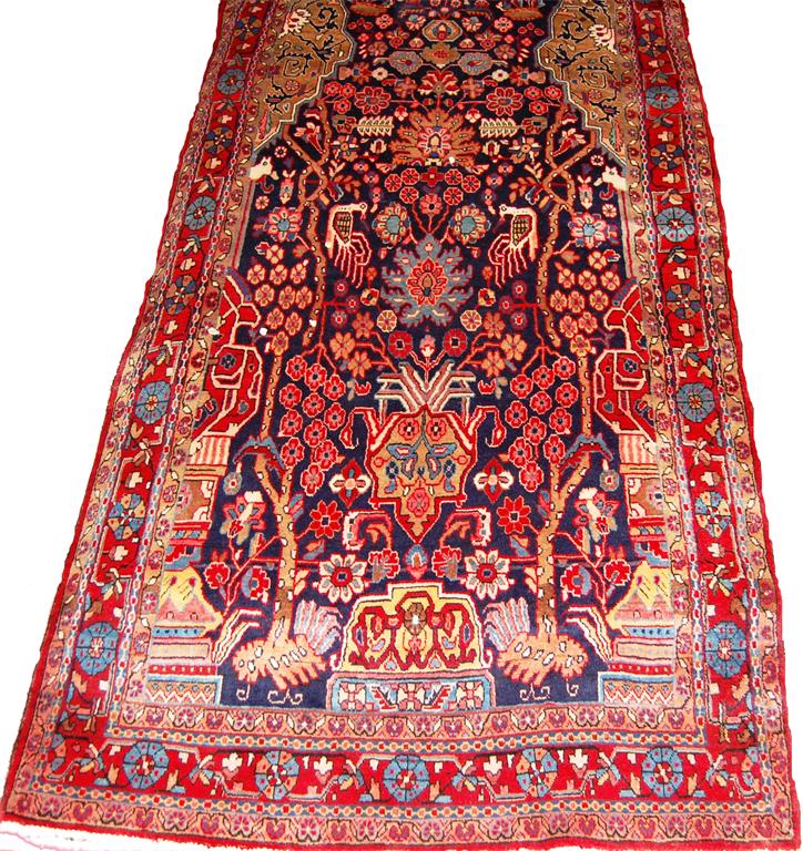 A Persian woollen pictorial rug, the complex blue ground decorated with flowers, trees and birds,