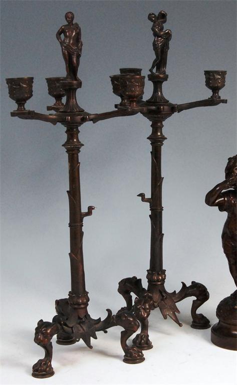 A pair of late 19th century Continental brass three light candelabra, each surmounted by robed