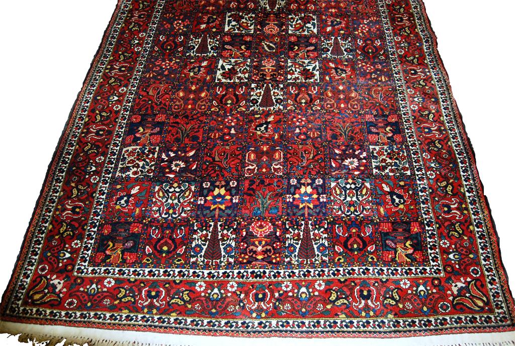 A Persian woollen carpet, having seven rows of boxed reserves, each decorated with stylised trees,