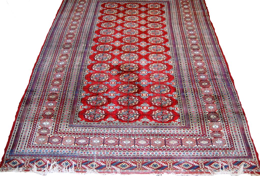 A Persian woollen Bokhara rug,  the red ground decorated with three rows of medallions within