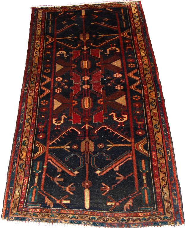 A Persian woollen rug, the black ground decorated with stylised animals and motifs within multiple