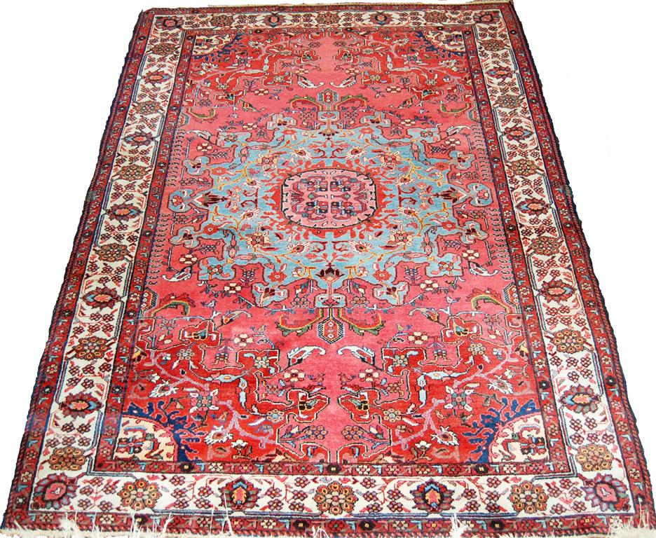 A Persian woollen red ground Tabriz rug, having a central medallion issuing scroll flowers and
