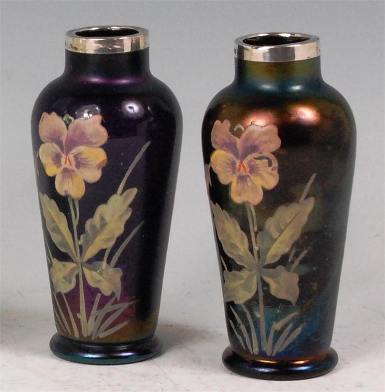 A pair of Art Nouveau iridescent glass vases, each having floral painted motif, and with silver