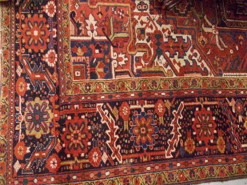 Heriz carpet of all-over medallion design with multiple borders on a red ground