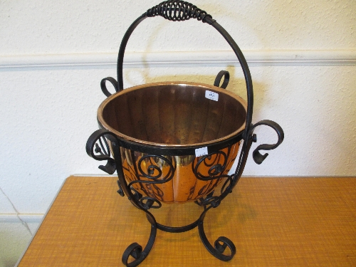 Circular copper coal bucket on wrought iron stand with swing handle