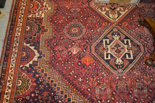 Shiraz carpet with medallion and all-over stylised floral design on red ground with borders