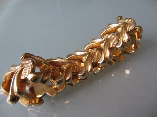 Modern yellow metal bracelet of stylised floral and scroll link design