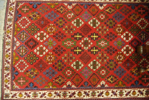 Pair of Joshaqan rugs with all-over stylised flower head designs on a red ground with borders