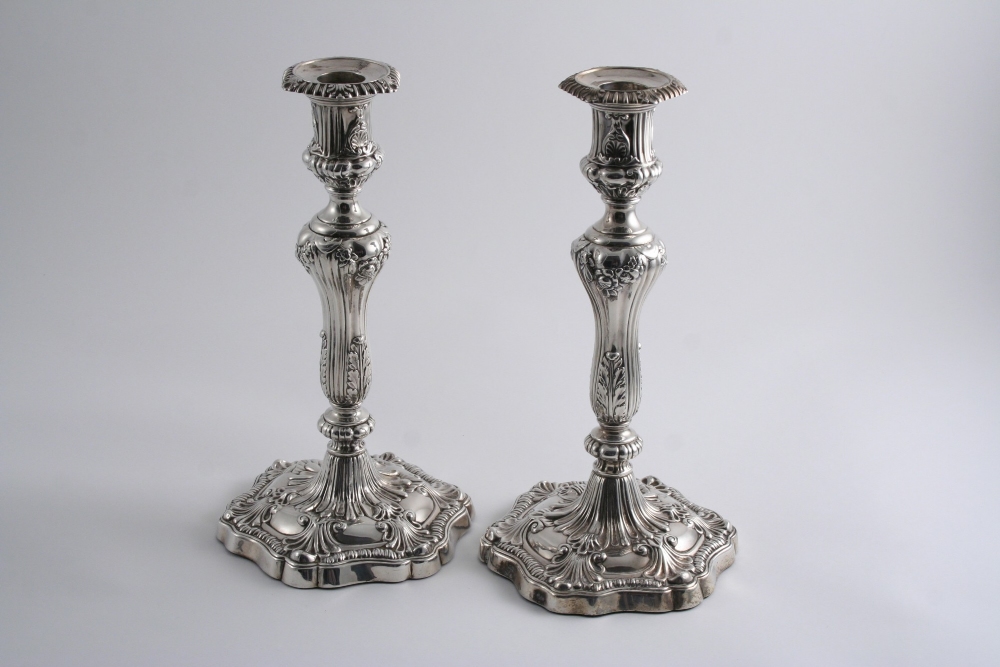 A PAIR OF GEORGE III CANDLESTICKS on shaped hexagonal bases with embossed decoration, baluster