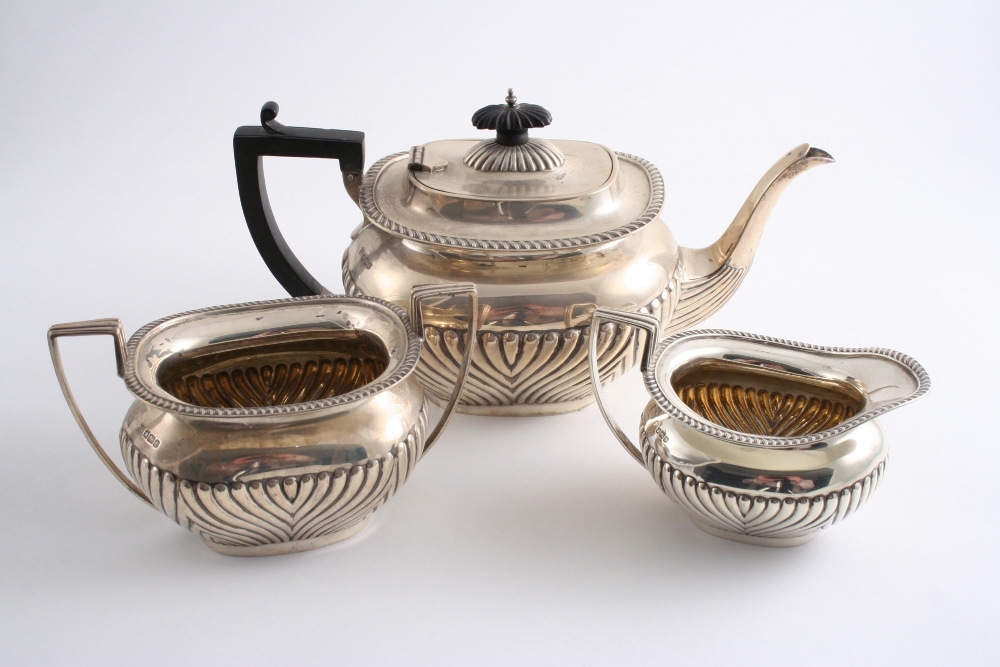 A MODERN THREE PIECE TEA SET of rounded oblong form with gadrooned borders & part-fluted decoration,