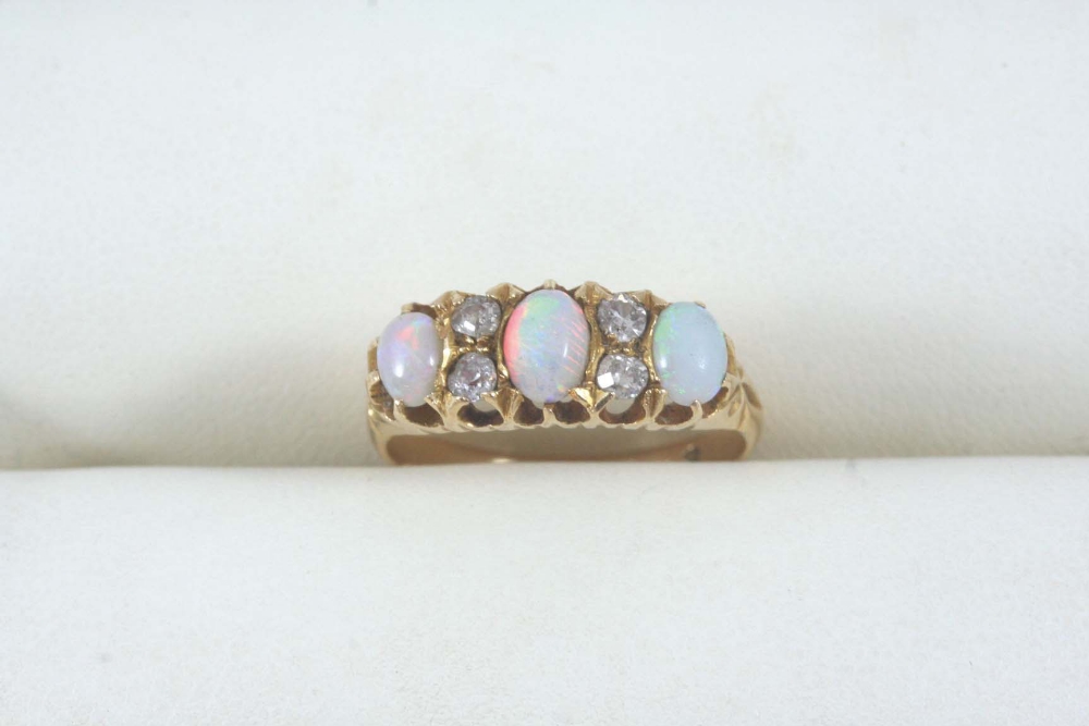 AN OPAL AND DIAMOND RING set with three graduated cabochon opals and four circular-cut diamonds,