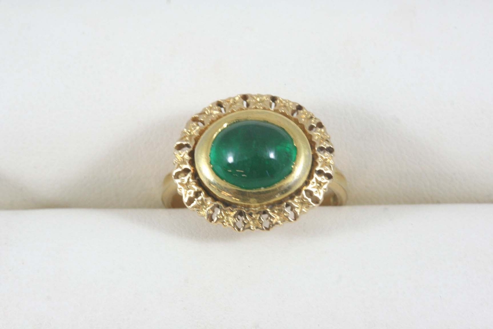 AN INDIAN EMERALD AND GOLD RING the oval-shaped cabochon emerald is set within a gold openwork