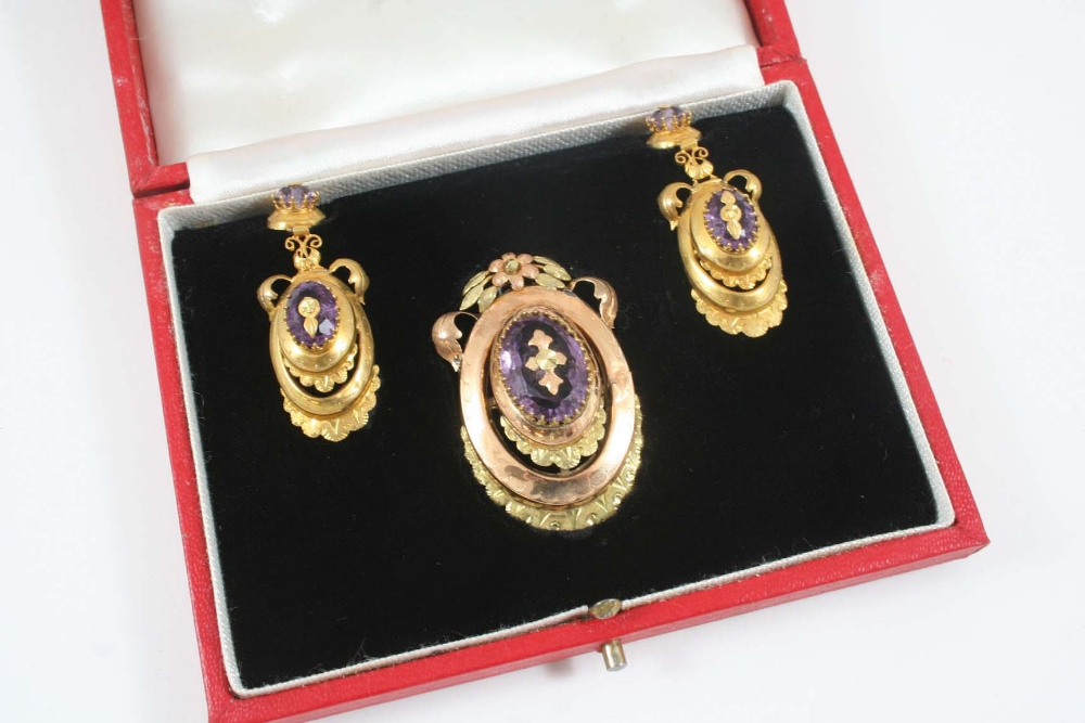 AN AMETHYST AND GOLD BROOCH the oval-shaped amethyst set with gold decoration within a foliate