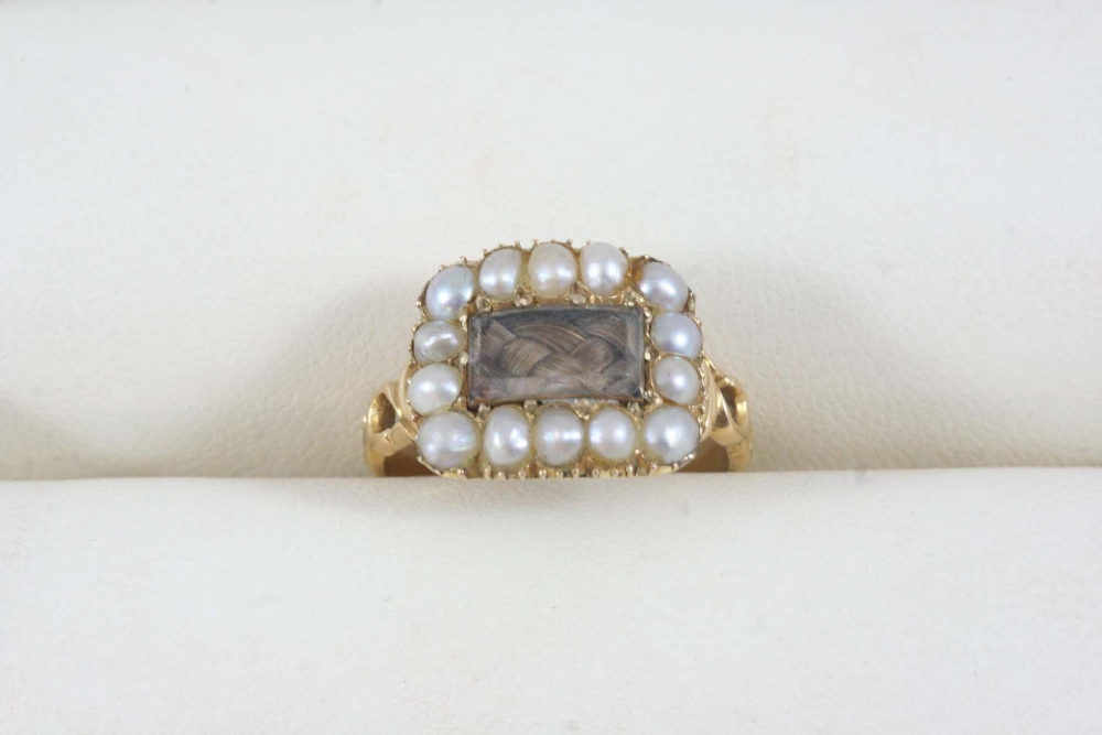 A VICTORIAN PEARL AND GOLD MOURNING RING the centre section containing hair is set within a surround