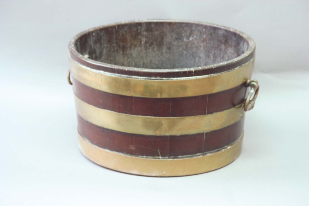 A GEORGE III MAHOGANY OYSTER BUCKET with brass bands and bold loop handles, 15 1/2ins. (39cms.) dia.