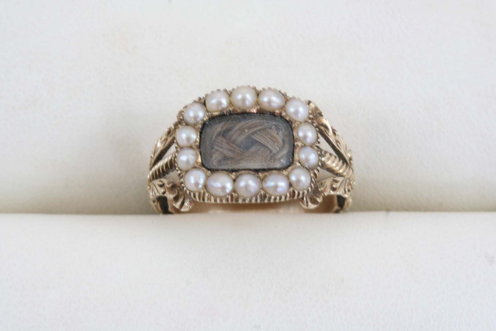 A WILLIAM IV GOLD AND PEARL MOURNING RING the centre section containing plaited hair within a