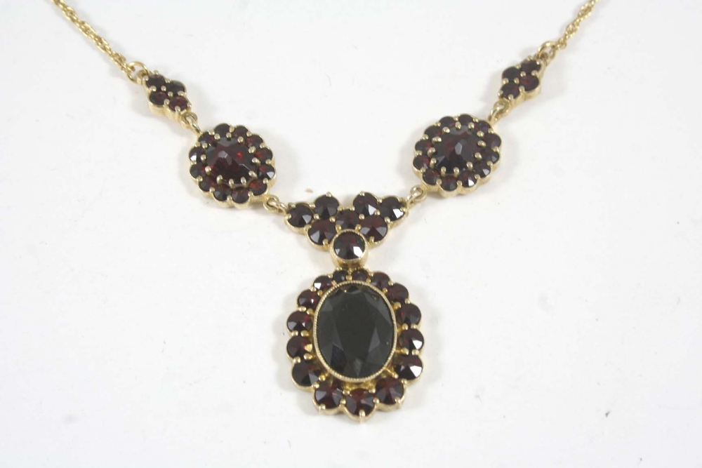 A MODERN GARNET FOLIATE NECKLACE formed with oval-shaped and circular-cut faceted garnets, in