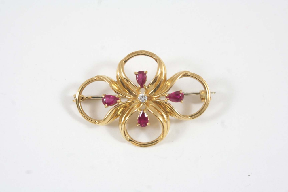 A RUBY AND DIAMOND QUARTREFOIL BROOCH centred with a small circular-cut diamond and with four pear-