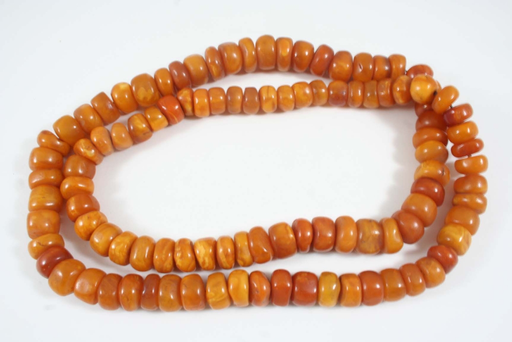 A GRADUATED AMBER NECKLACE formed with irregular amber roundells, 98cm. long, 180 grams.
