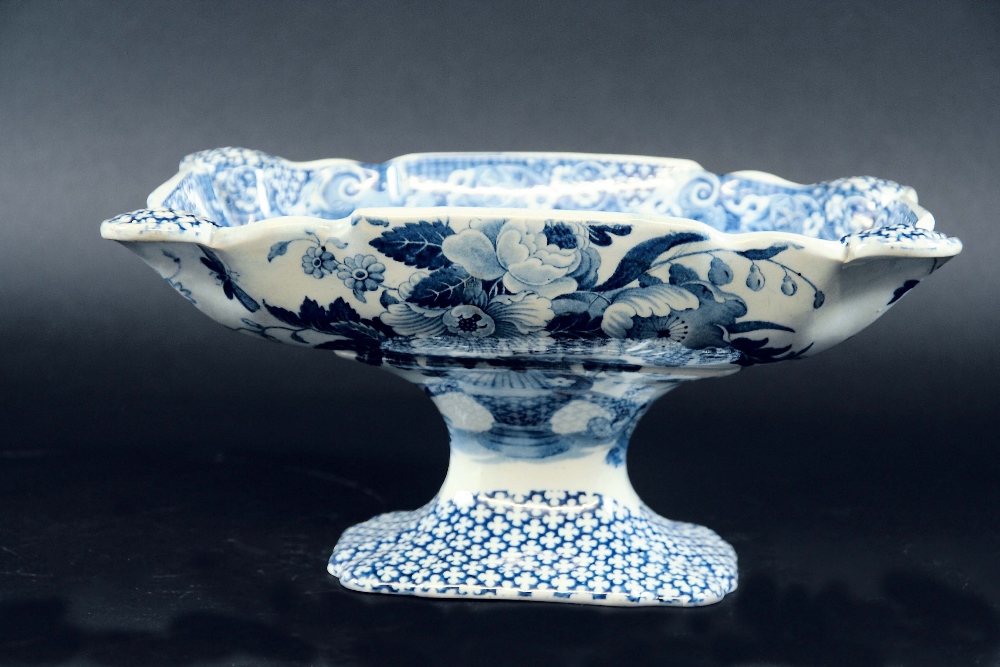 A LOVICKS BLUE AND WHITE FOOTED COMPORT printed with a flower filled urn and scrolls, 10 3/4ins. (