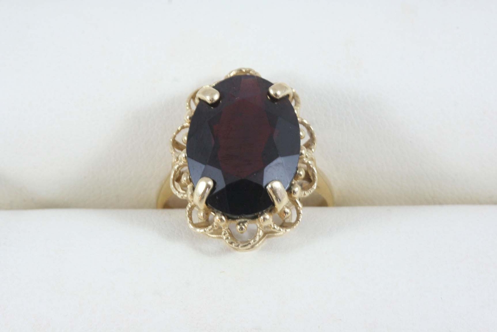 A GARNET SINGLE STONE RING set with an oval-shaped garnet, in gold. Size O.