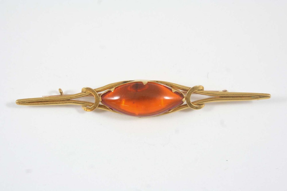 AN AMBER BROOCH the lozenge-shaped cabochon amber is set in gold, 8.5cm. long.