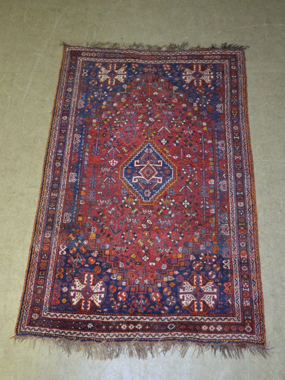A Turkish madder ground rug, the central lozenge shaped field centred with a lozenge shaped panel