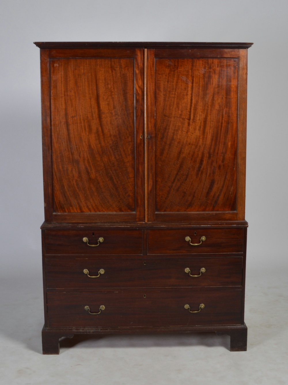 A George III mahogany linen press, the moulded cornice above a pair of panelled cupboard doors,